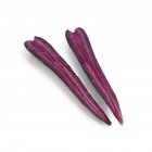 Black carrot cut into halves on white background. — Stock Photo