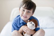 Мальчик с плюшевой обезьяной в больничной койке . — стоковое фото