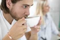 Close-up view of man drinking coffee in kitchen. — Stock Photo