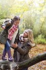 Famille jouant sur le tronc d'arbre dans les bois en automne . — Photo de stock