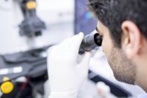 Male scientist using microscope, close-up. — Stock Photo