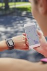Woman checking time on sports smartwatch and smartphone. — Stock Photo