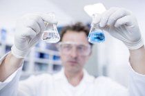 Male laboratory assistant holding chemical flasks. — Stock Photo