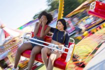 Two young women having fun on amusement ride. — Stock Photo