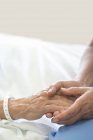 Nurse holding male patient hand in hospital bed. — Stock Photo