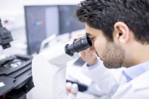 Male scientist using microscope, close-up. — Stock Photo