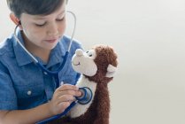 Ragazzo che gioca con stetoscopio e scimmia ripiena . — Foto stock