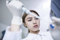 Female lab assistant using pipette, close-up. — Stock Photo
