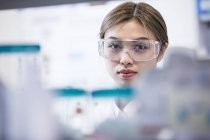 Assistente de laboratório feminina usando óculos de segurança . — Fotografia de Stock