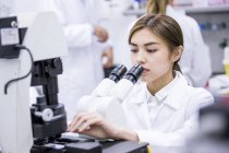 Cientista feminina usando microscópio em laboratório . — Fotografia de Stock