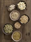 Legumes in bowls on chopping board, overhead view. — Stock Photo