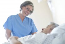 Infirmière parlant à un patient masculin dans un lit d'hôpital . — Photo de stock