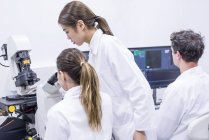 Cientistas trabalhando em laboratório com microscópio e computador
. — Fotografia de Stock