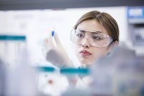 Female laboratory assistant wearing safety goggles. — Stock Photo