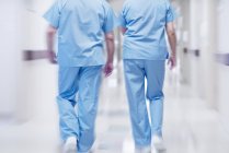 Dois médicos vestindo esfoliação cirúrgica andando no corredor, visão traseira . — Fotografia de Stock