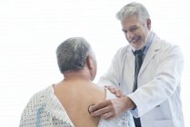 Homme médecin examinant patient en robe d'hôpital . — Photo de stock