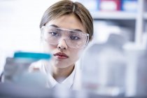 Female laboratory assistant wearing safety goggles. — Stock Photo