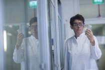 Химик в защитных очках держит образец в фармацевтической лаборатории . — стоковое фото