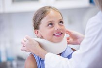 Girl with neck support looking at doctor. — Stock Photo