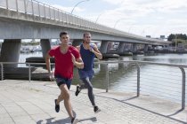 Atleti maschi che corrono sulla riva del fiume . — Foto stock