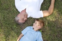 Дедушка и внук лежат лицом к лицу на траве . — стоковое фото