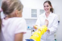 Arzt legt Mädchen gelbe Beinstrebe an. — Stockfoto