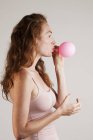 Perfil de young woman with red hair soprando up pink balloon . — Fotografia de Stock