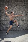Vista lateral del hombre saltando con baloncesto . - foto de stock