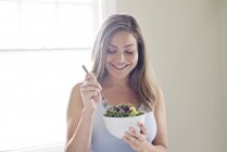 Donna che mangia ciotola di insalata vegetale — Foto stock