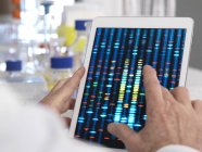 Visualizzazione da parte degli scienziati dei risultati dei test genetici su tablet digitale . — Foto stock