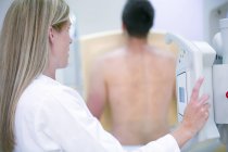 Médecin féminin examinant la poitrine masculine avec radiographie . — Photo de stock
