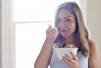 Mujer comiendo tazón de ensalada de verduras - foto de stock