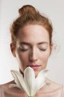 Woman with eyes closed smelling white flower. — Stock Photo