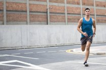 Hombre en ropa deportiva corriendo por la carretera . - foto de stock