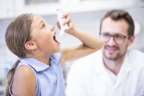 Mädchen mit Inhalator, während männlicher Arzt zusieht. — Stockfoto