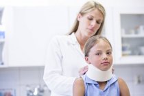 Female doctor applying neck support to young girl. — Stock Photo