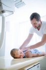 Male doctor positioning girl on X-ray machine. — Stock Photo