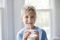 Preadolescente niño bebiendo batido con paja - foto de stock