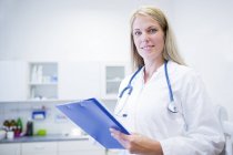 Female doctor standing with clipboard, portrait. — Stock Photo