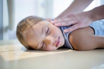 Jeune fille couchée sur la radiographie avec les mains du médecin sur le dos . — Photo de stock