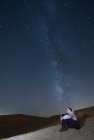 Scenic view of teenager looking up at stars of Milky Way galaxy. — Stock Photo