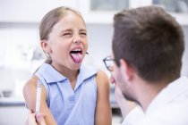 Medico prendendo campione di tampone da ragazza bocca . — Foto stock