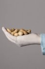 Hand in latex glove holding peanuts — Stock Photo