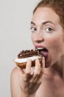 Retrato de mulher comendo donut de chocolate . — Fotografia de Stock
