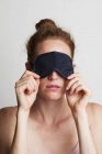 Tired woman wearing sleeping mask covering eyes. — Stock Photo