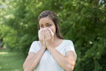 Woman blowing nose on tissue outdoors. — Stock Photo
