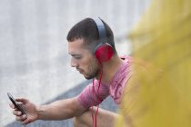 Человек в наушниках слушает музыку на смартфоне . — стоковое фото