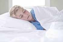 Boy sleeping on bed indoors. — Stock Photo