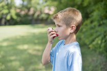 Boy using inhaler outdoors. — Stock Photo