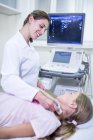 Sonographer performing ultrasound on girl neck. — Stock Photo